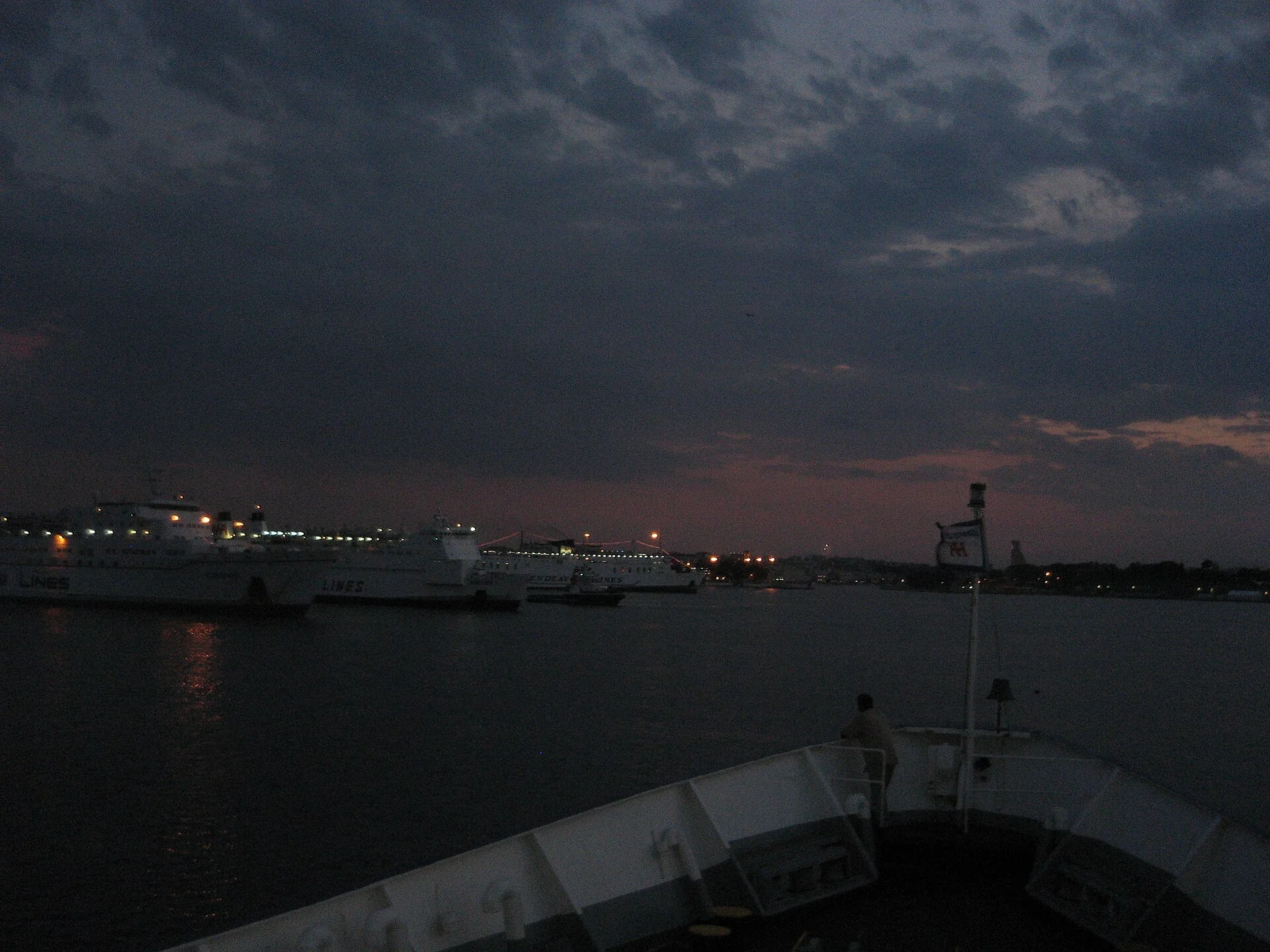 Brindisi harbor illuminated at night with boats reflected in calm waters